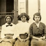 Photo of three young African American women sitting on the steps of a porch, 1920s